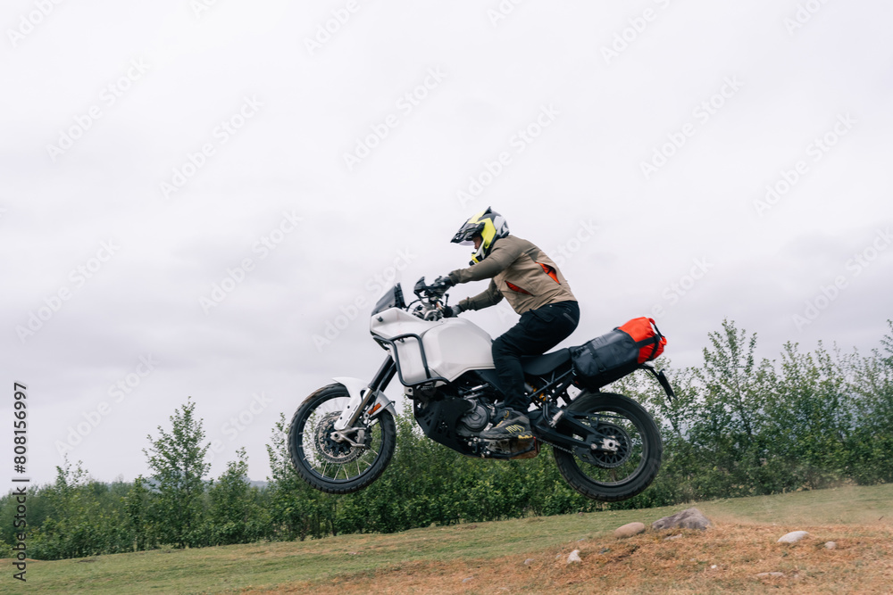 Motorcyclist jumping on adventure tourist enduro motorcycle outdoor on training area Motorcyclist jumping on adventure tourist enduro motorcycle outdoor on training area