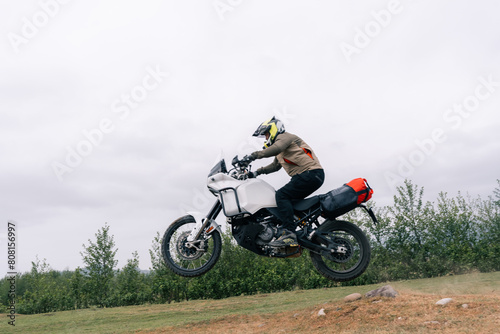 Motorcyclist jumping on adventure tourist enduro motorcycle outdoor on training area