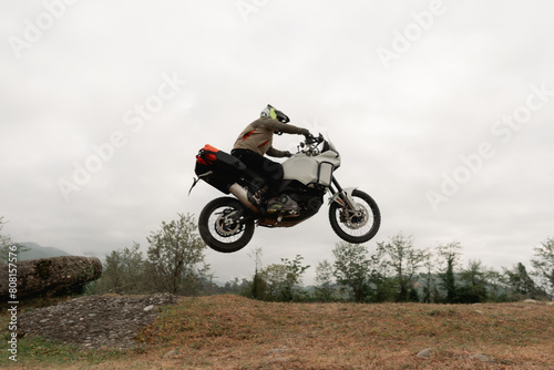 Motorcyclist jumping in moto trip on adventure tourist enduro motorcycle outdoor offroad in mountains