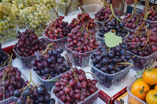 Eye catching display of fresh red, green and purple grapes at a farmers market.