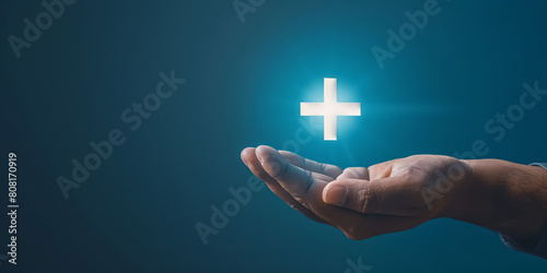 Close up of male hand holding glowing cross on dark background. Medicine and healthcare concept.  photo
