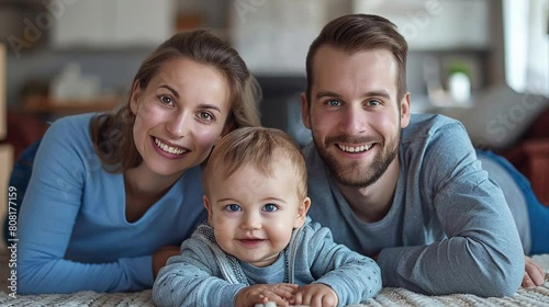 A radiant young family of three shares a cheerful moment, lying together on a cozy carpet at home.