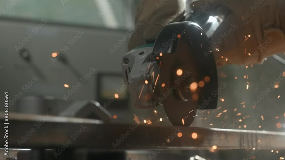 Craftsman working with grinder at industrial plant, man grinding iron detail, sparks flying around and falling on the ground in workshop. Close up shot.