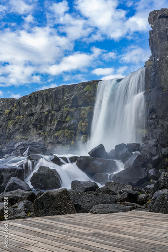Oxararfoss  spectacular Icelandic waterfall.   ingvellir National Park. Cold water falls on large black boulders of volcanic origin.