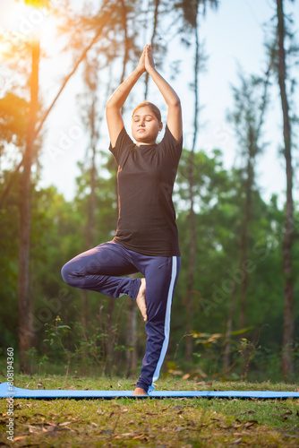 indian women practicing Vrksasana or tree pose at outdoor during early morning