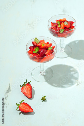 Strawberry healthy dessert with lemon sauce, honey and mint leaves in crystal vintage glasses, sunlight, mint background. Healthy summer, spring recipes, natural vitamins, summer vibes