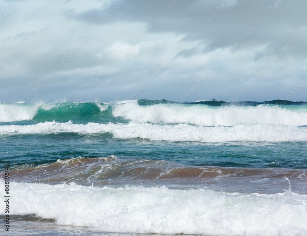 Ocean storm waves with foam and splashes. View from beach.