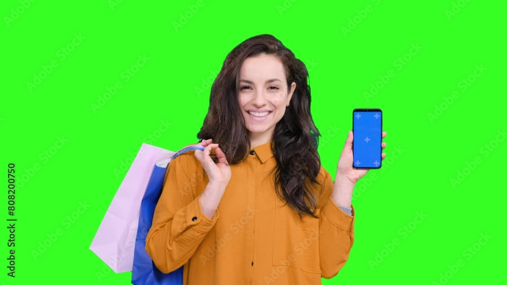 Smiling woman with shopping bags, showing phone screen on the chroma key Smiling woman with shopping bags, showing phone screen on the chroma key