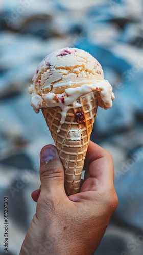 hand holding an ice cream cone against a blurred background. photo