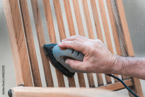 Close-up of Man Sanding a Wooden Chair photo