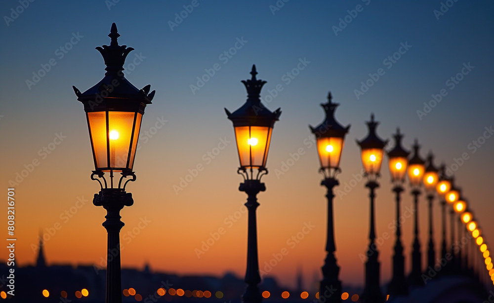 Row of street lamps at dusk where one lamp is lit up and the others remain off.