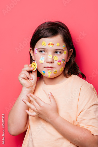 School girl with emoji stickers on face and hands photo