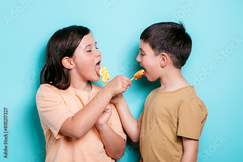 Cheerful school kids sharing candies on turquoise background photo