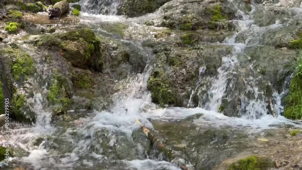 Water cascades over moss-covered rocks in a vibrant forest stream, creating a lively and refreshing scene. Water cascades over moss-covered rocks in a vibrant forest stream, creating a lively and refreshing scene.