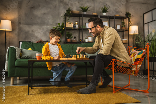 Father and son play chess together at home