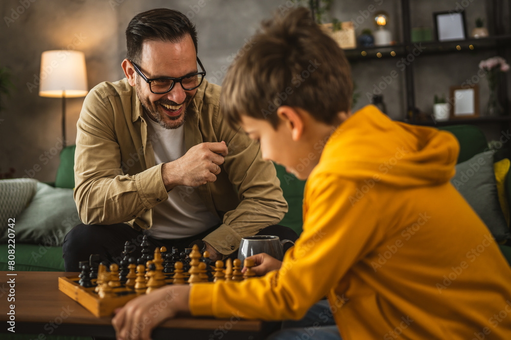 Father and son play chess together at home Father and son play chess together at home
