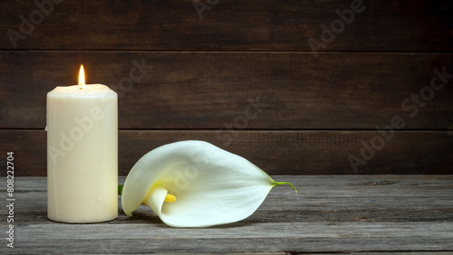 LIGHTED CANDLE AND CALLA FLOWER ON WOODEN BACKGROUND. DEAD DAY, FUNERAL, ALL SOULS DAY. COPY SPACE.	