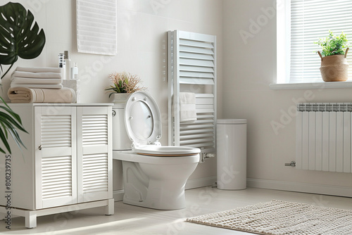 A white toilet with a storage cabinet and bathroom accessories in the background