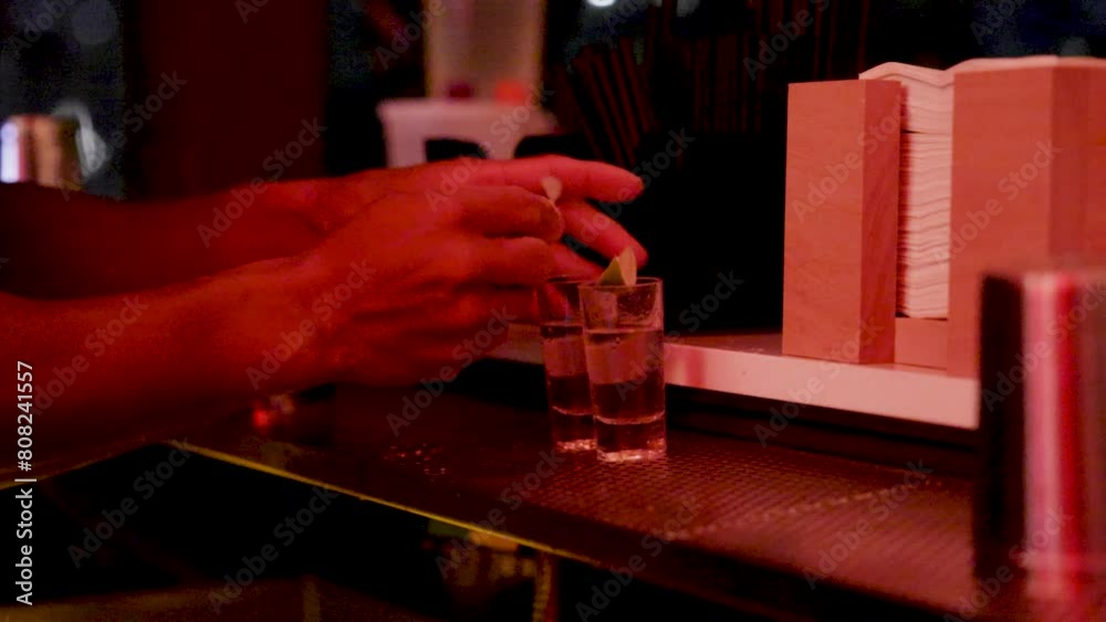 The bartender pours alcohol into a glass with ice