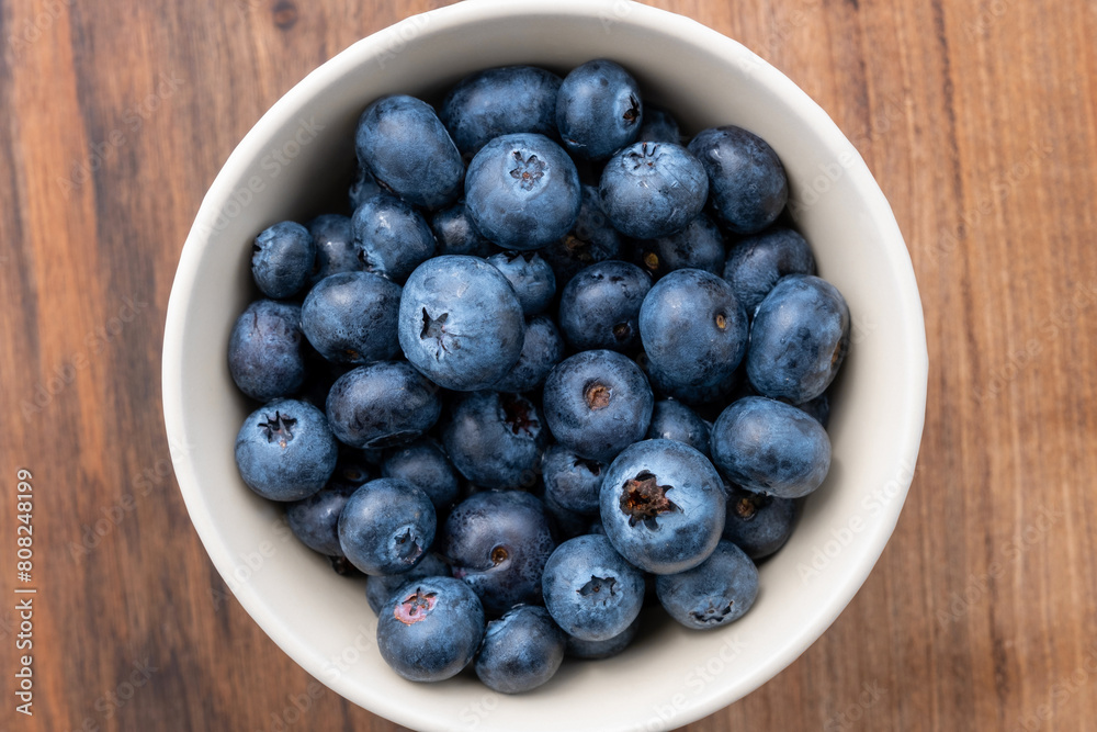 Top view of blueberries in bowl on wooden table Top view of blueberries in bowl on wooden table
