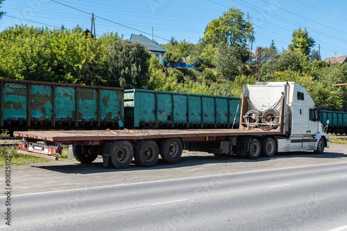 White long distance bonnet truck with a semitrailer at a freight railway station in the countryside