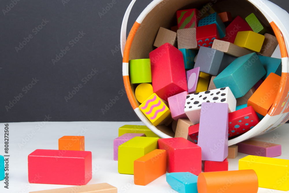 Naklejka premium Children's toy, wooden constructor, poured out of a bucket on a black background. Kids toys.