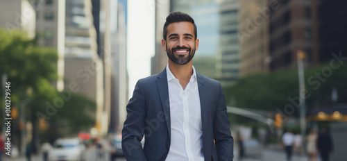 Confident happy smiling mature Hispanic businessman standing in the city and looking at camera