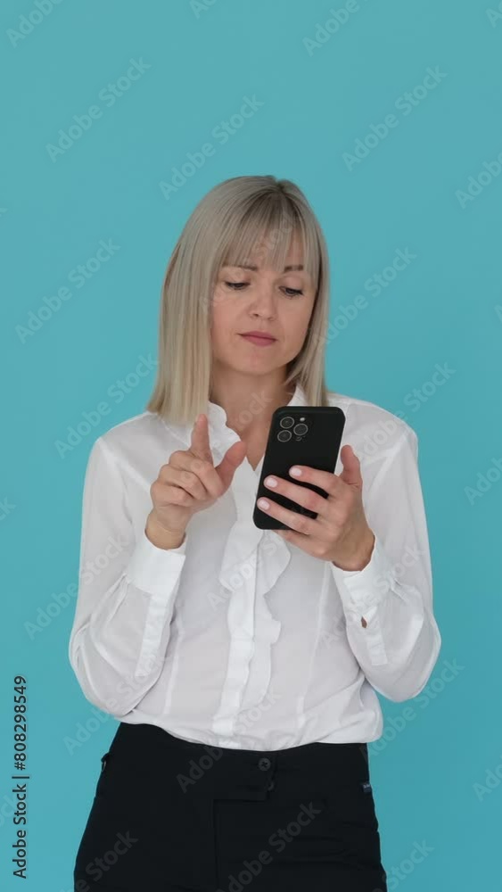 Bored Caucasian businesswoman using mobile phone and yawning on blue background. Boredom, tiredness, fatigue, unhappiness. Vertical video. Bored Caucasian businesswoman using mobile phone and yawning on blue background. Boredom, tiredness, fatigue, unhappiness. Vertical video.