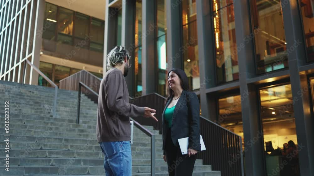 Businesspeople shake hands celebrating a business deal in a modern urban setting. Adult man and woman shake hands to finalise a business deal. Businesspeople shake hands celebrating a business deal in a modern urban setting. Adult man and woman shake hands to finalise a business deal.