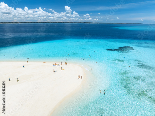 Aerial view of Nakupenda island, sandbank in ocean, white sandy beach, blue sea during low tide at sunny summer day in Zanzibar. Top view of sand spit, clear water, people, sky with clouds. Tropical