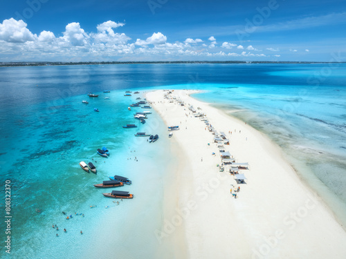 Aerial view of Nakupenda island, sandbank in ocean, white sandy beach, boats, blue sea during low tide at sunny summer day in Zanzibar. Top view of sand spit, clear water, sky with clouds. Tropical