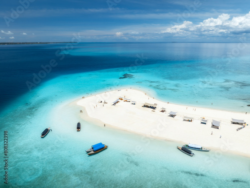 Aerial view of Nakupenda island, sandbank in ocean, white sandy beach, boats, blue sea during low tide at sunny summer day in Zanzibar. Top view of sand spit, clear water, sky with clouds. Tropical