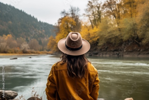 woman in yellow jacket standing by river in autumn