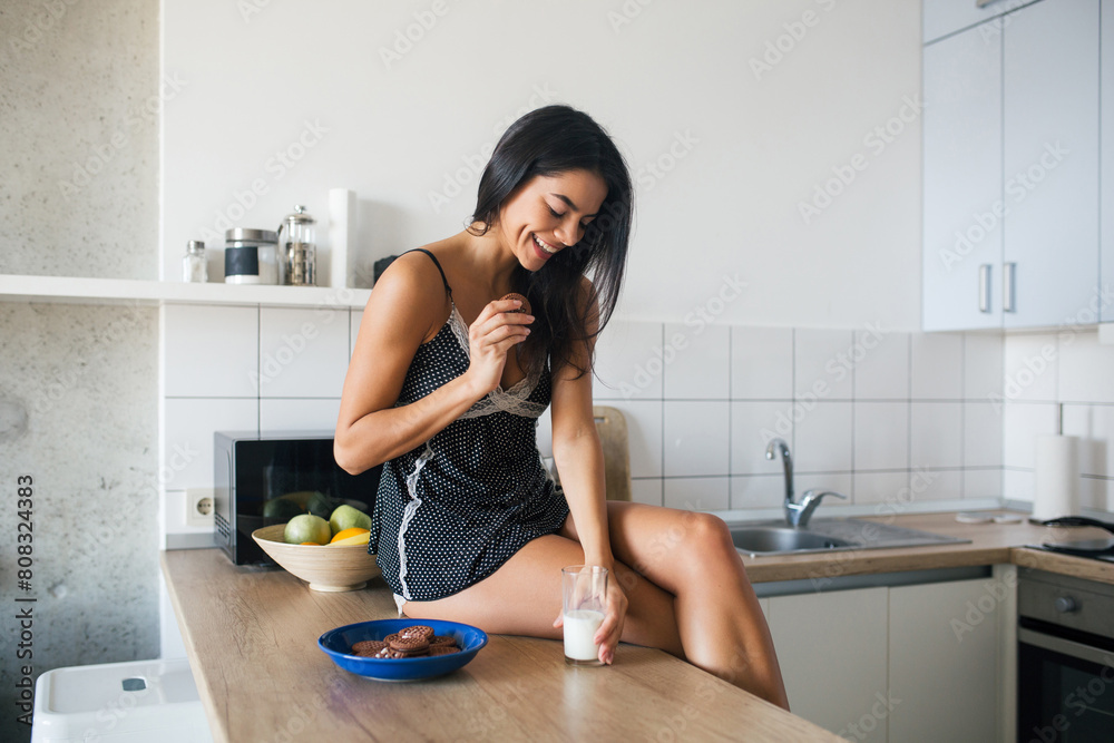attractive smiling woman in pajamas having breakfast in kitchen attractive smiling woman in pajamas having breakfast in kitchen