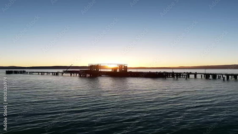 Aerial view of sunset shining through the pier in peaceful evening. Vertical. Aerial view of sunset shining through the pier in peaceful evening. Vertical.