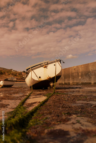 Fishing boats moored, at low tide, at Nefyn Port, Gwynedd, North Wales. Taken in evening sunlight.