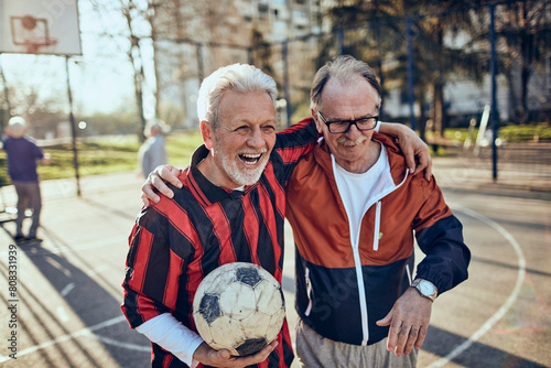 Senior men playing soccer and discussing strategy in urban park