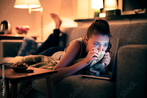 Woman watching a sad movie on laptop at home photo