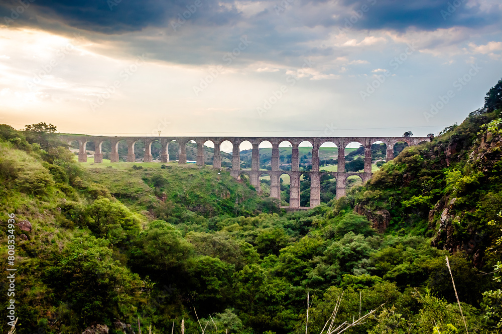 Aqueduct between mountains at sunset with cloudy sky in arcos del sitio in tepotzotlan state of mexico