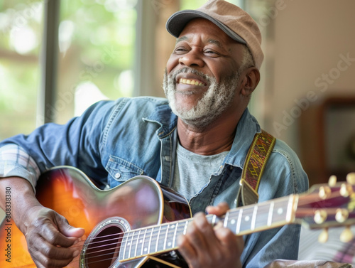 A black man playing the acoustic guitar, smiling with his eyes closed.  Shallow dof.