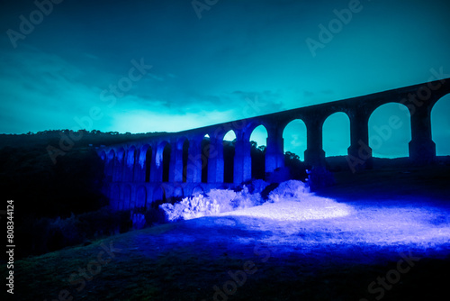 Aqueduct at night illuminated with blue light in arcos del sitio in tepotzotlan state of mexico photo
