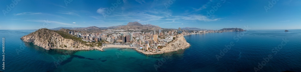 Fototapeta premium Extremely wide panoramic aerial drone photo of the town of Benidorm in Spain in the summer time showing the beach known locally as Playa de Finestrat and hotels and apartments around the small beach