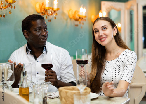 Loving cheerful positive smiling pair enjoying evening meal and conversation at cozy restaurant