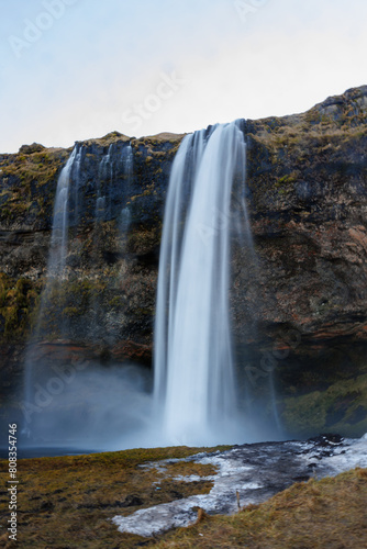 Water flow from icelandic stones forming nordic waterfall and falling down hill. Scandinavian magnificent seljalandsfoss cascade sits in a wintry setting and illustrating arctic nature.