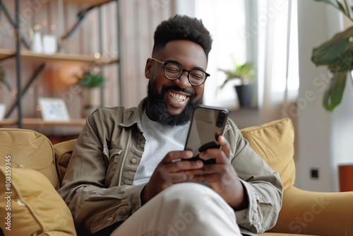smiling african american man in eyeglasses using smartphone at home