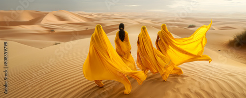 Poster with silhouettes of women in yellow saris standing among the harsh beauty of the desert and sand dunes, drought and desertification of the earth, the harsh beauty of nature