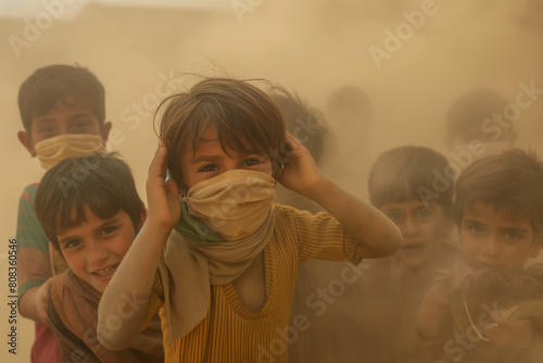 Smiling Child with Scarf Covering Mouth Amidst Dusty Air and Blurred Figures.