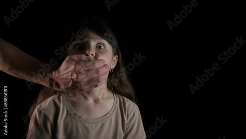 Man palm close child mouth. A man palm close little child mouth against black background. A concept of young victim and home abuse during childhood.