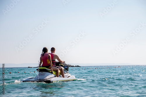 Couple riding jet ski and enjoying the view on the sea.