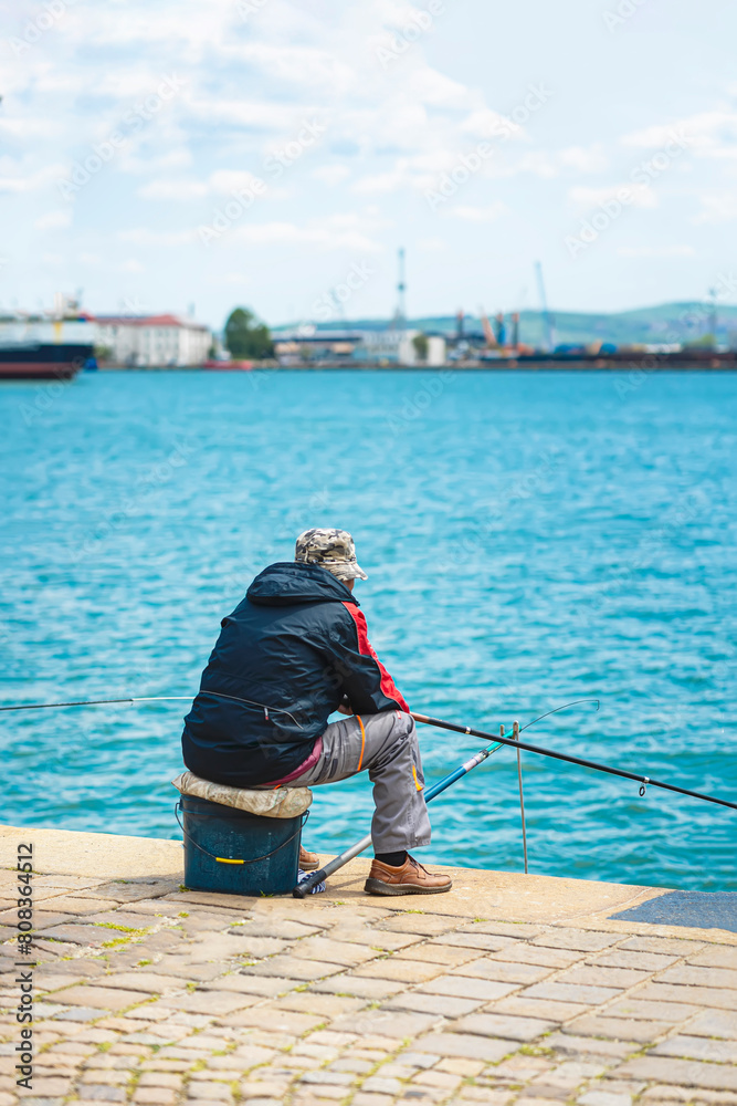 Fisherman on pier, back view. Leisure time, relaxing on fishing